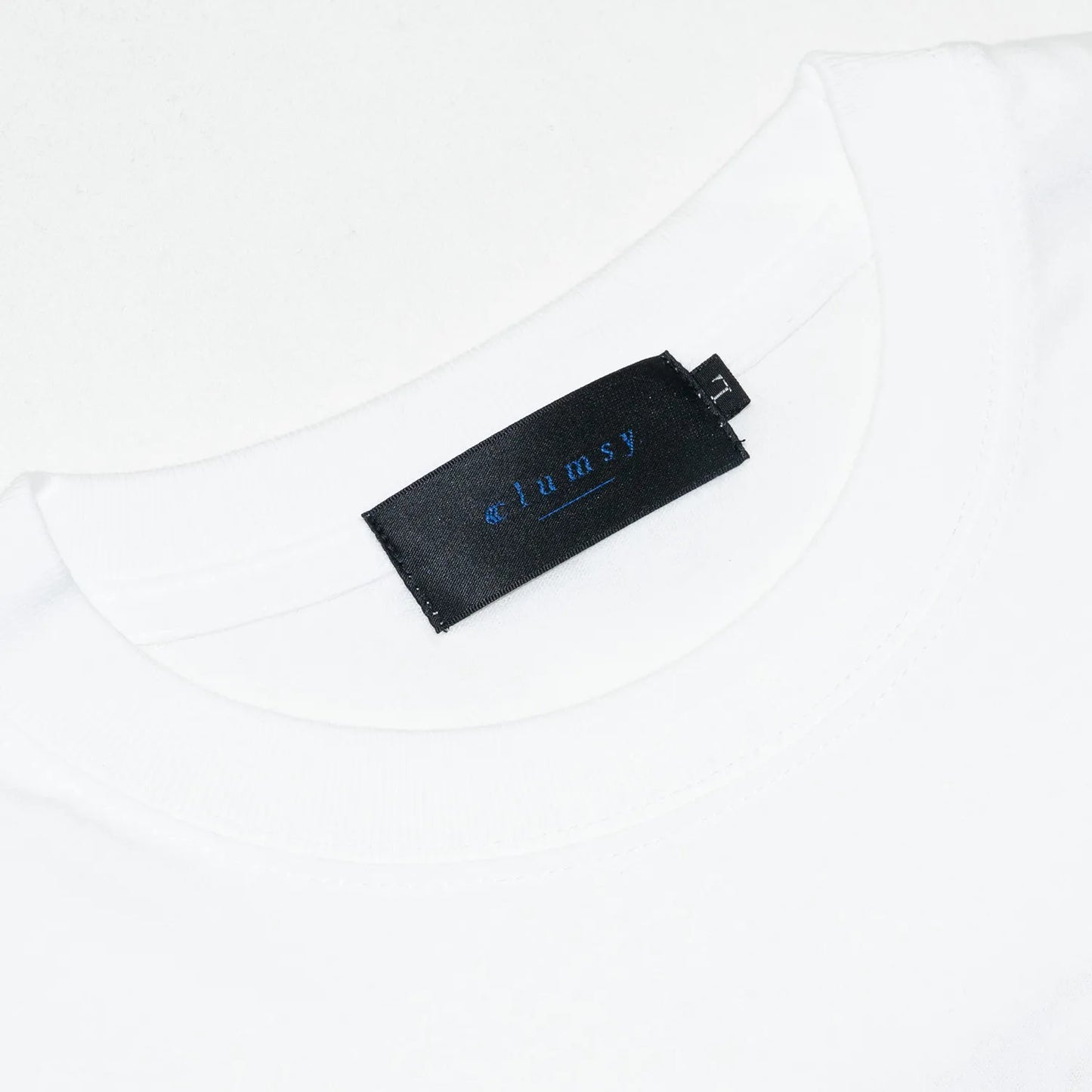 clumsy. Pictures(クラムジー)のCCCロゴが背面に大きくプリントされた定番アイテム「LIMITED CCC」ロングスリーブのWHITE/ROUGEカラー襟裏のブランドタグの写真
