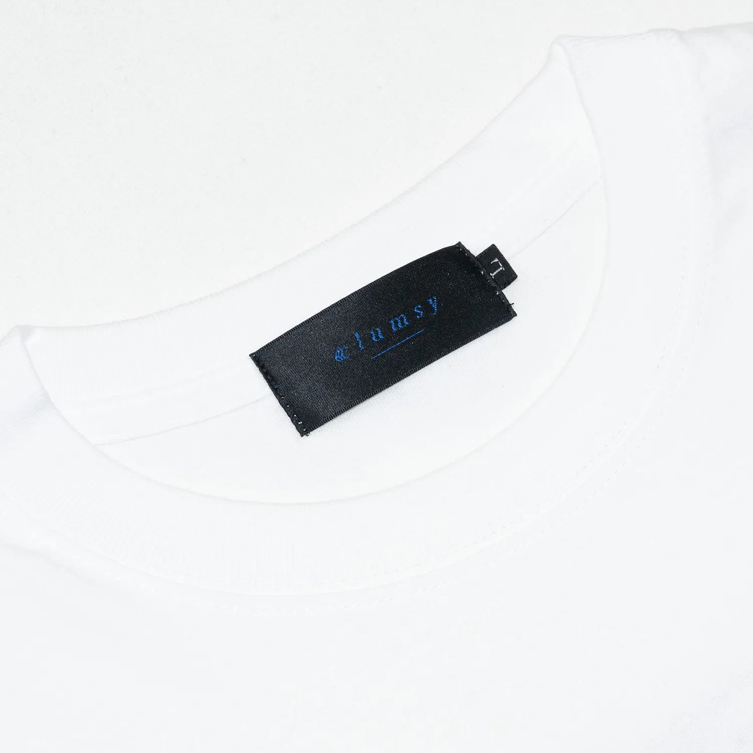clumsy. Pictures(クラムジー)のCCCロゴが背面に大きくプリントされた定番アイテム「LIMITED CCC」ロングスリーブのWHITE/ROUGEカラー襟裏のブランドタグの写真