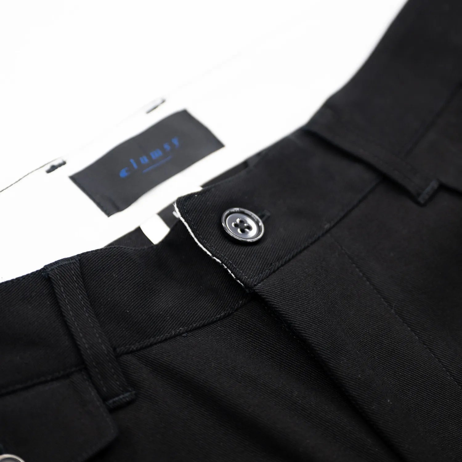 CLUMSY PICTURESの新作パンツ「2 PLEATS RELAXED TWILL PANTS」のBLACKカラーの腰回りの商品写真