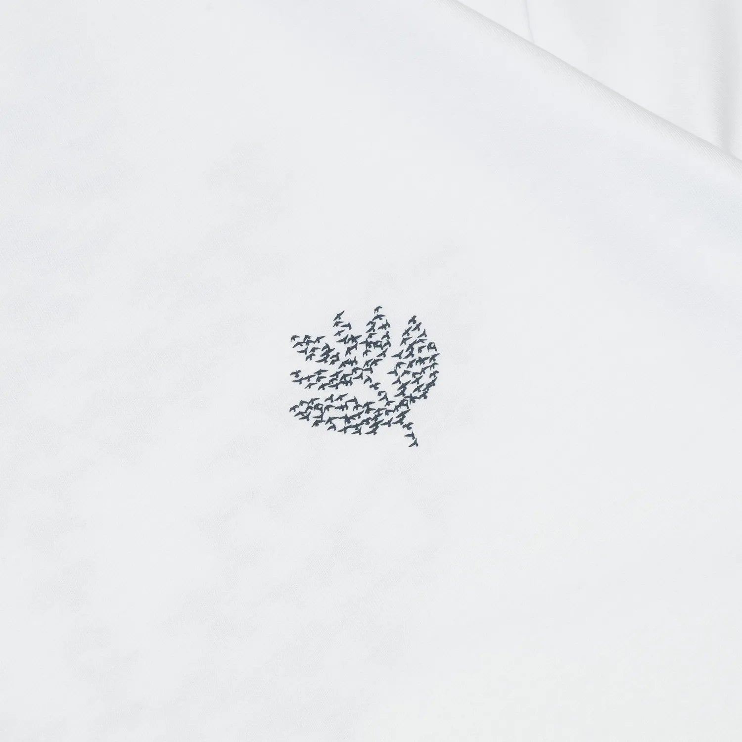 MAGENTA(マジェンタ)のTシャツ「MIGRATION S/S TEE」のWHITEカラーの正面左胸のデザインの写真