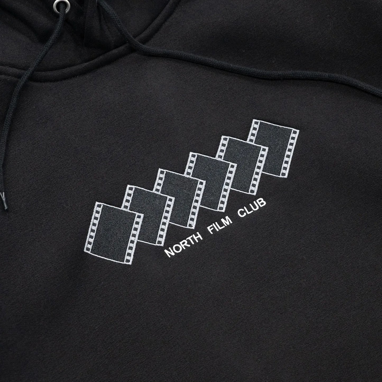 NORTH SKATE MAG(ノーススケートマグ)のフロントにデザインが刺繍で入る肉厚なパーカー「FILM CLUB HOODIE」のBLACKカラーの正面デザインの写真
