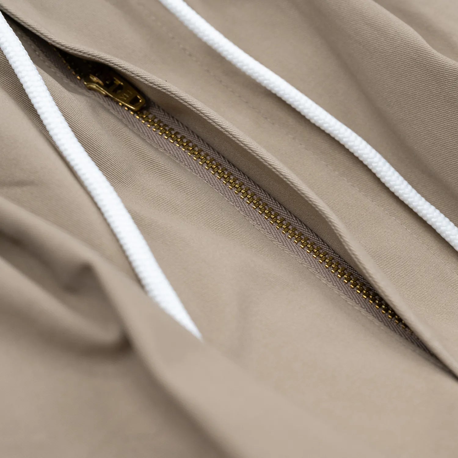 CLUMSY PICTURES(クラムジー)の大定番チノをイージーパンツ仕様に作り変えた「2 PLEATS RELAXED EASY PANTS」のBEIGEカラーのジップアップとドローコードの写真