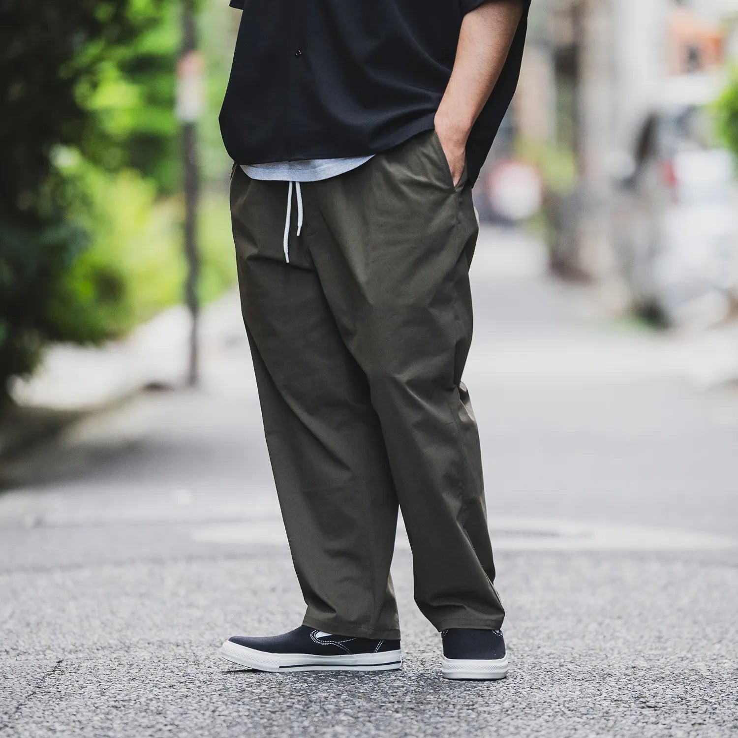 clumsy.Pictures(クラムジー)の傑作チノパンをイージーパンツタイプに作り替えた「2 PLEATS RELAXED EASY PANTS」の「OLIVE BROWN」カラーの斜め正面からの着用写真