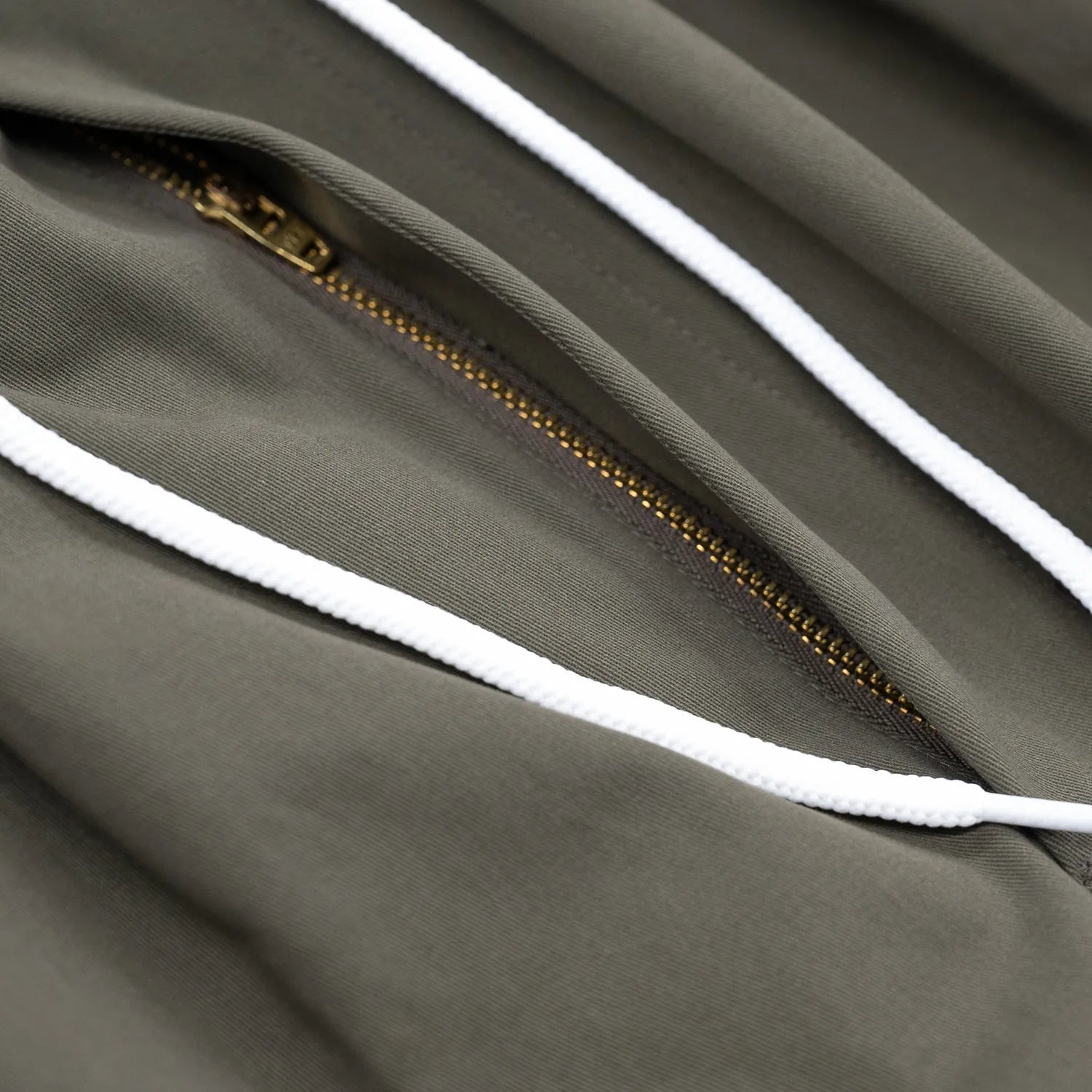 CLUMSY PICTURES(クラムジー)の大定番チノをイージーパンツ仕様に作り変えた「2 PLEATS RELAXED EASY PANTS」のOLIVE BROWNカラーのジップアップとドローコードの写真
