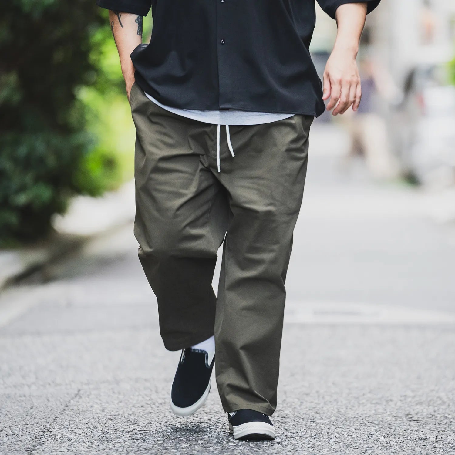 clumsy.Pictures(クラムジー)の傑作チノパンをイージーパンツタイプに作り替えた「2 PLEATS RELAXED EASY PANTS」の「OLIVE BROWN」カラーの歩きながらの着用写真の別カット