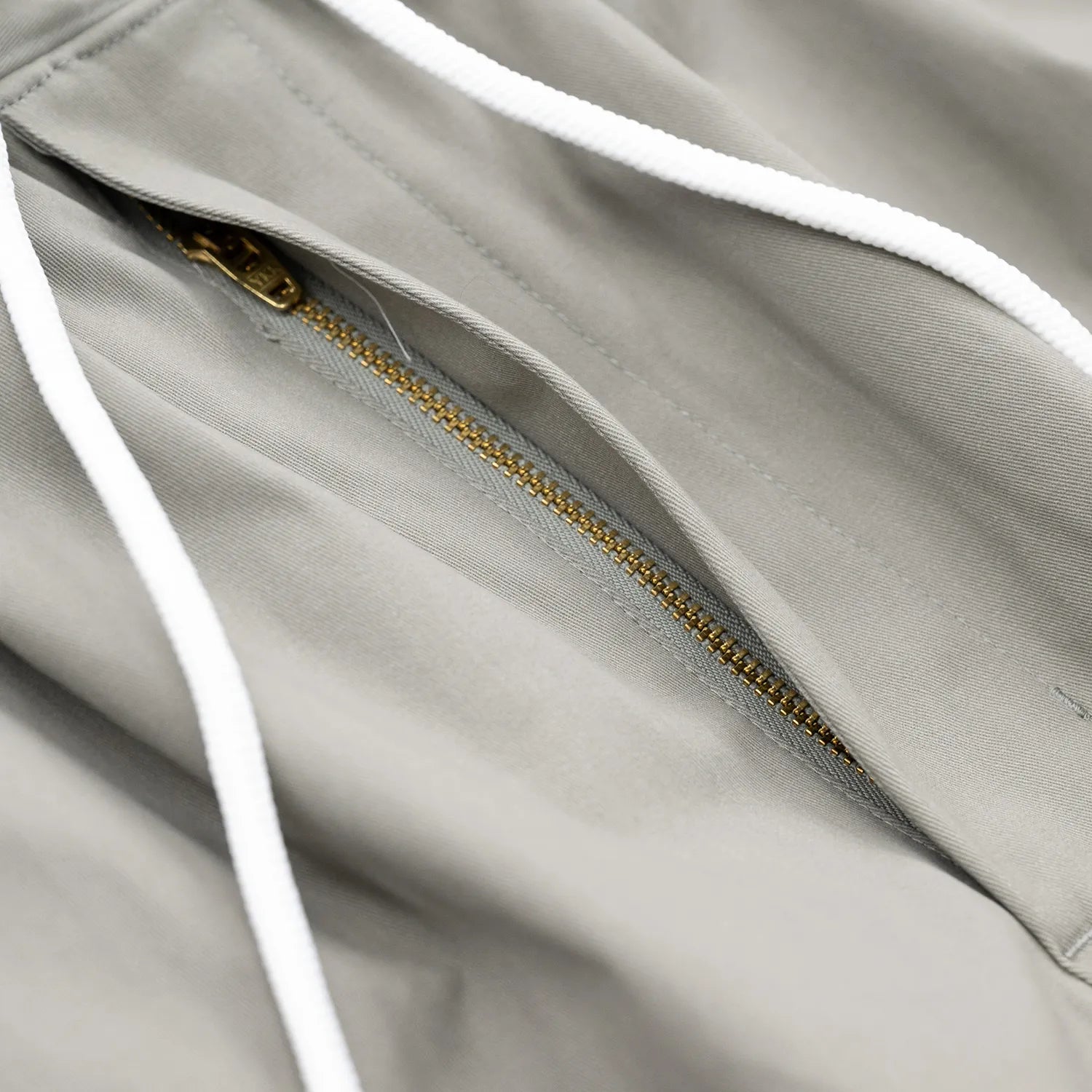 CLUMSY PICTURES(クラムジー)の大定番チノをイージーパンツ仕様に作り変えた「2 PLEATS RELAXED EASY PANTS」のSLATE GREYカラーのジップアップとドローコードの写真