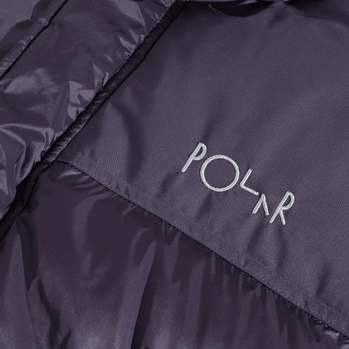 POLAR SKATE CO(ポーラースケート)の600フィルパワーのダウンベスト「BASIC PUFFER VEST」のDARK VIOLETカラーの正面左胸のブランドロゴの刺繍デザインの写真