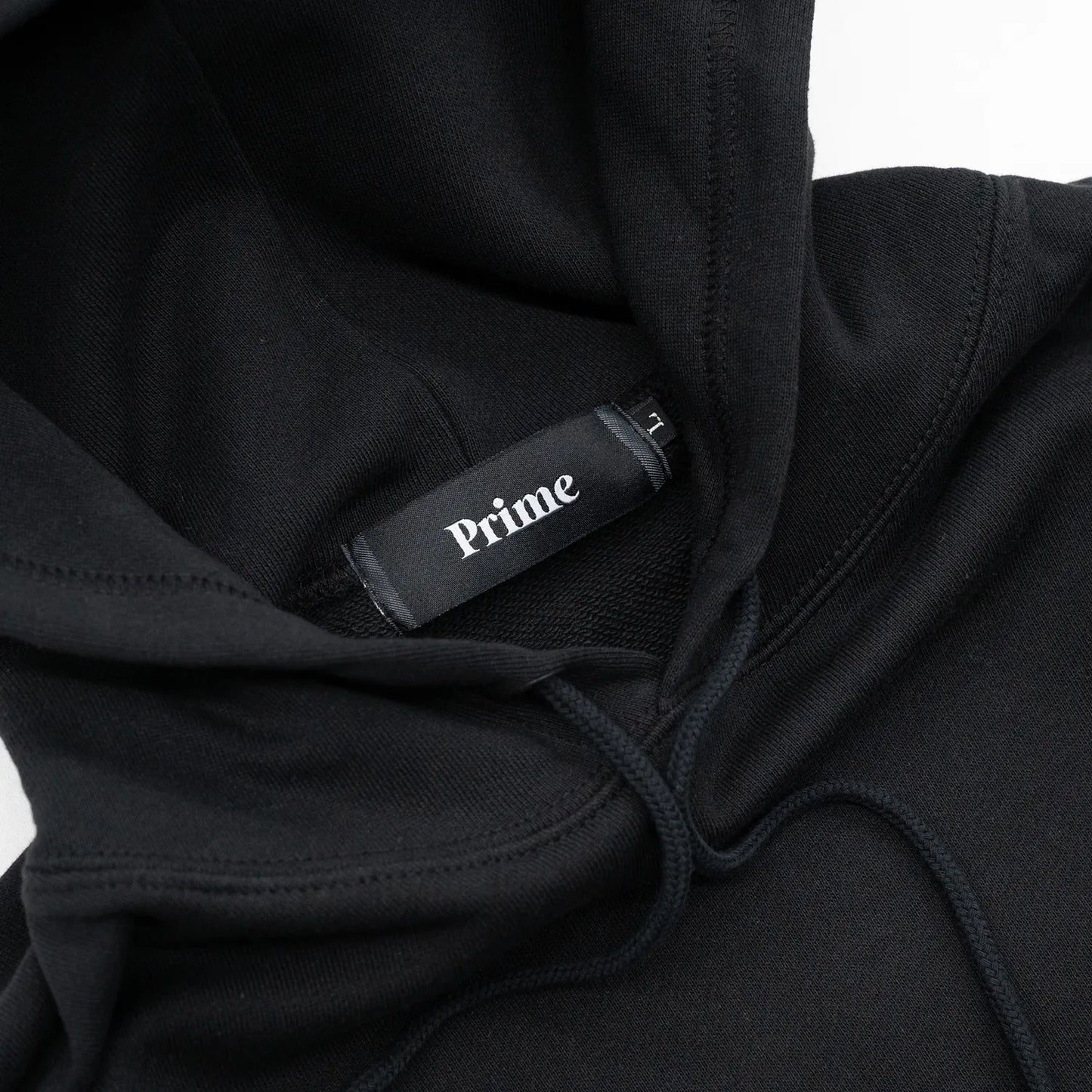 Primeのパーカー・フーディ「PRIME GALLERY BAR LOGO HOODY」のBLACKカラーの襟裏のブランドタグ