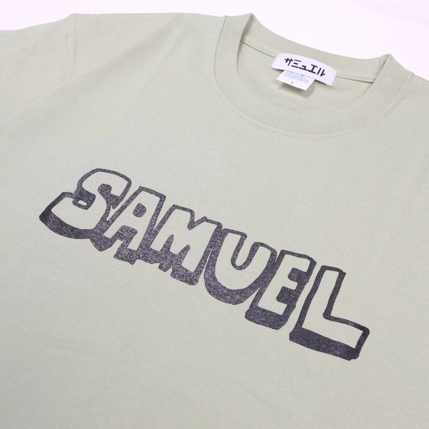 スチャダラパーのANI(アニ)氏とナオヒロック(IIIIINOUT)による「SAMUEL」の定番グラフィックのTシャツ「DAT TEE」のSAGE GREENカラーの正面のメイングラフィック写真