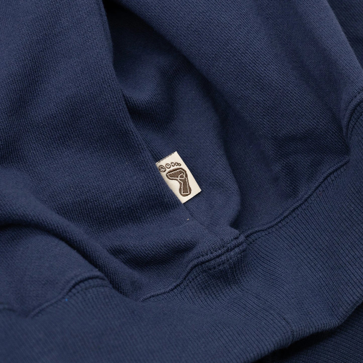 TRIBE WEAR(トライブウェア)の肉厚なフーディー|パーカー「BASIC HOODIE」のNAVYカラーの左脇下のブランドタグ写真