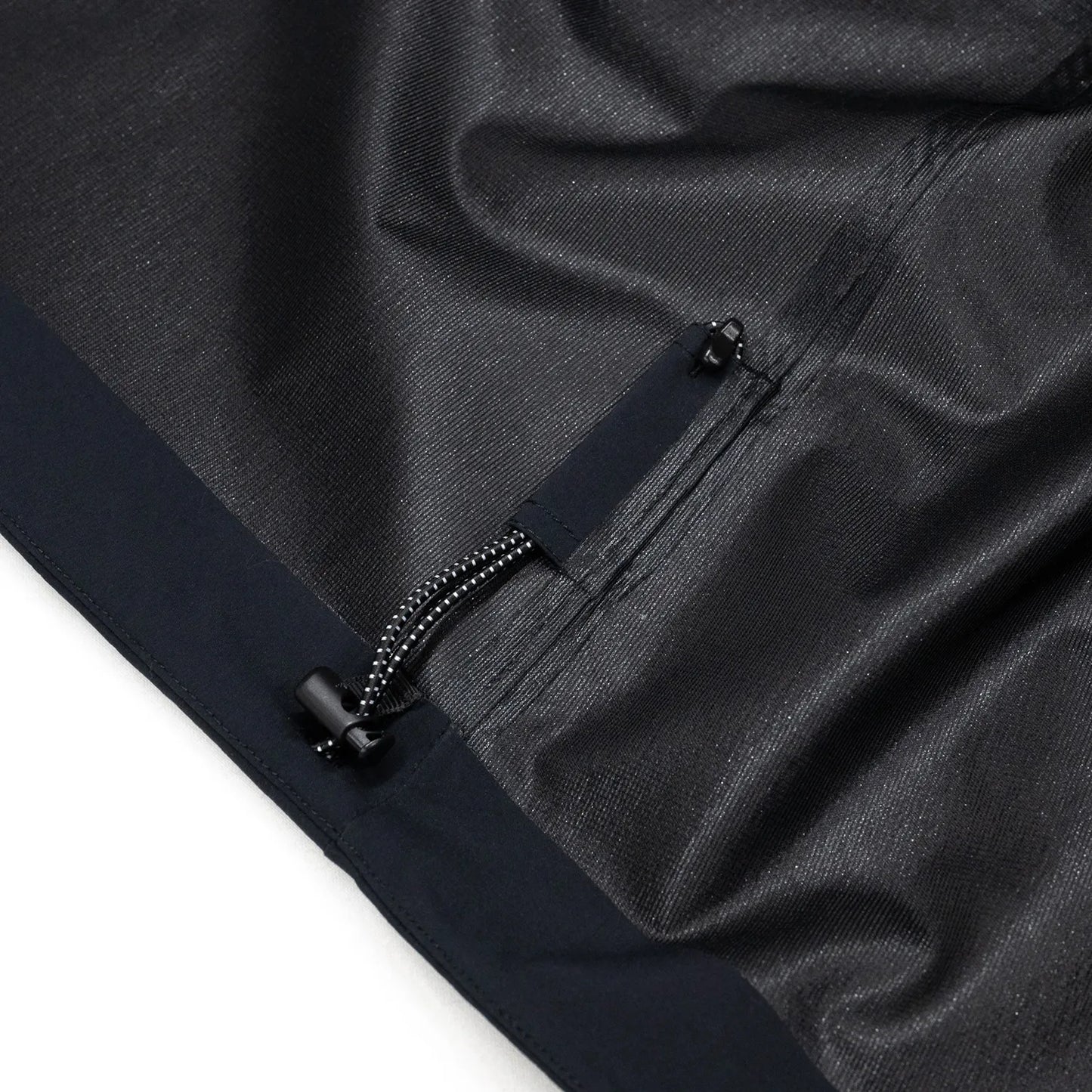 米軍の「ECWCS LEVEL6 JACKET GEN1 後期型」をベースにAndersが再構築したの3LAYERコート「3LAYERS ECWCS HARD SHELL COAT」のMATT BLACKカラーの裾部分のドローコードの写真
