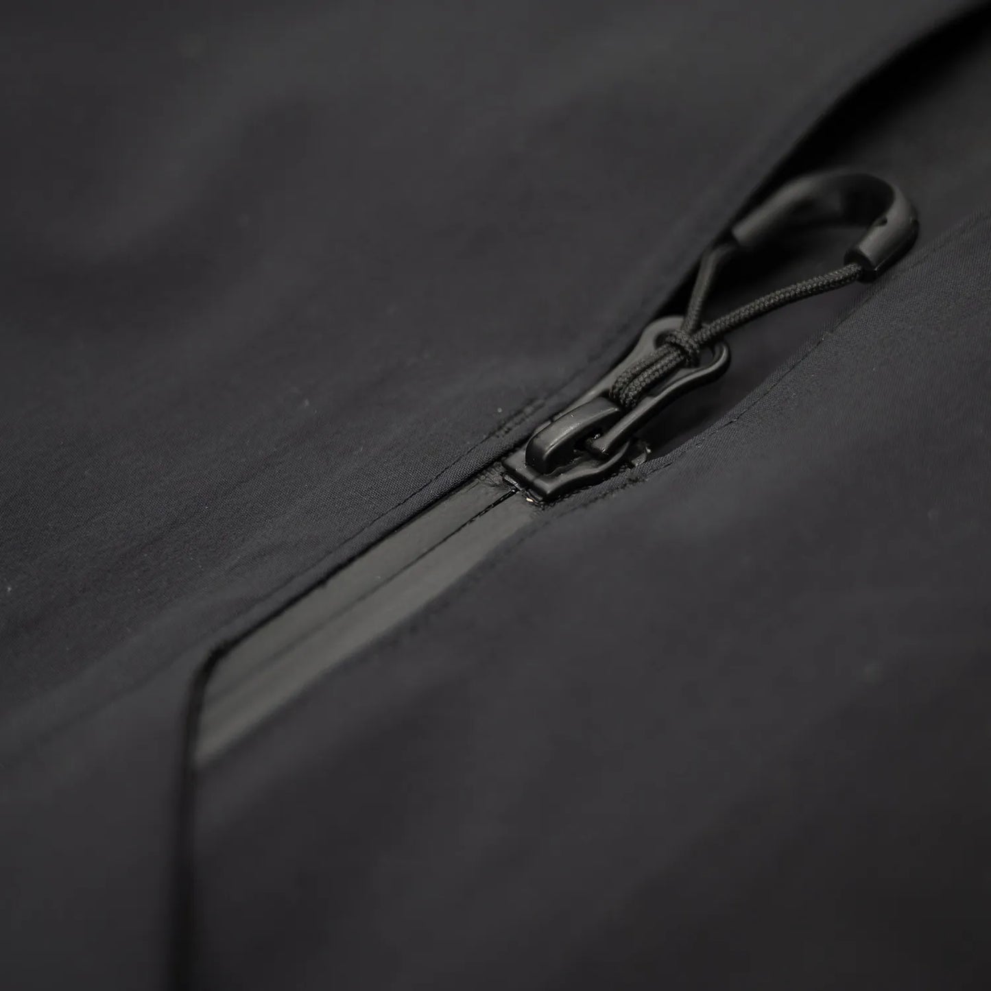 米軍の「ECWCS LEVEL6 JACKET GEN1 後期型」をベースにAndersが再構築したの3LAYERコート「3LAYERS ECWCS HARD SHELL COAT」のMATT BLACKカラーのジップアップ部分の写真
