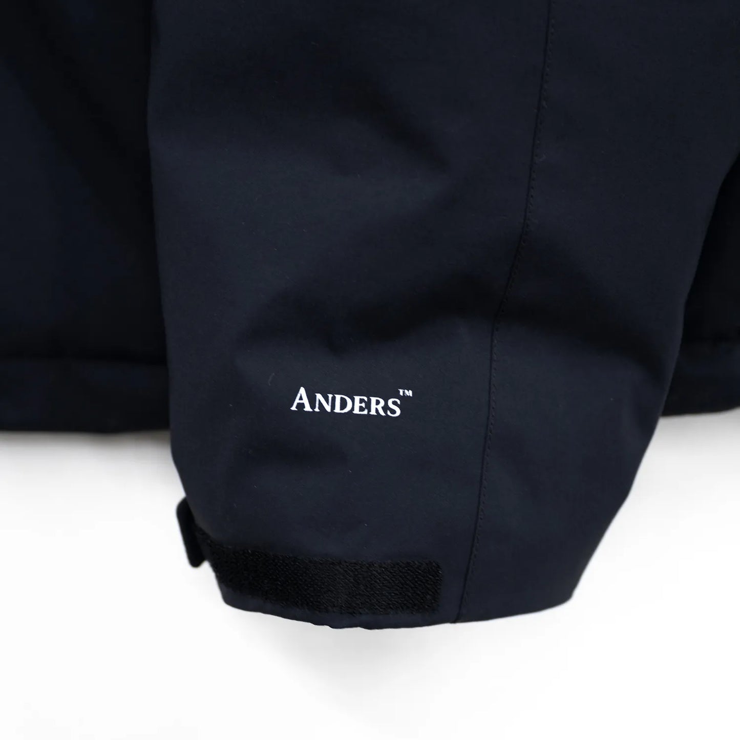 米軍の「ECWCS LEVEL6 JACKET GEN1 後期型」をベースにAndersが再構築したのハードシェル・パファージャケット「3LAYERS ECWCS HARD SHELL PUFFER JACKET」のMATT BLACKカラーの袖部のロゴデザイン写真