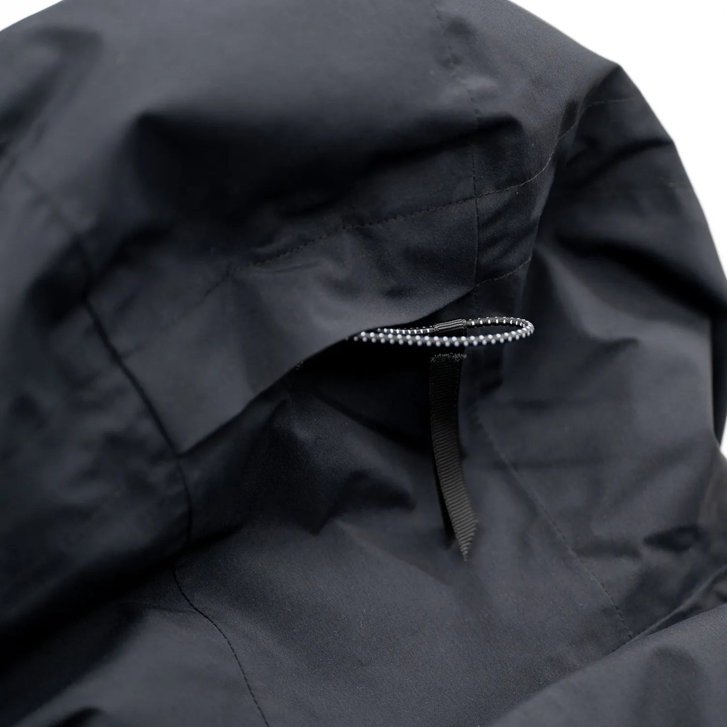 米軍の「ECWCS LEVEL6 JACKET GEN1 後期型」をベースにAndersが再構築したのハードシェル・パファージャケット「3LAYERS ECWCS HARD SHELL PUFFER JACKET」のMATT BLACKカラーのフード裏のアジャスターコードの写真