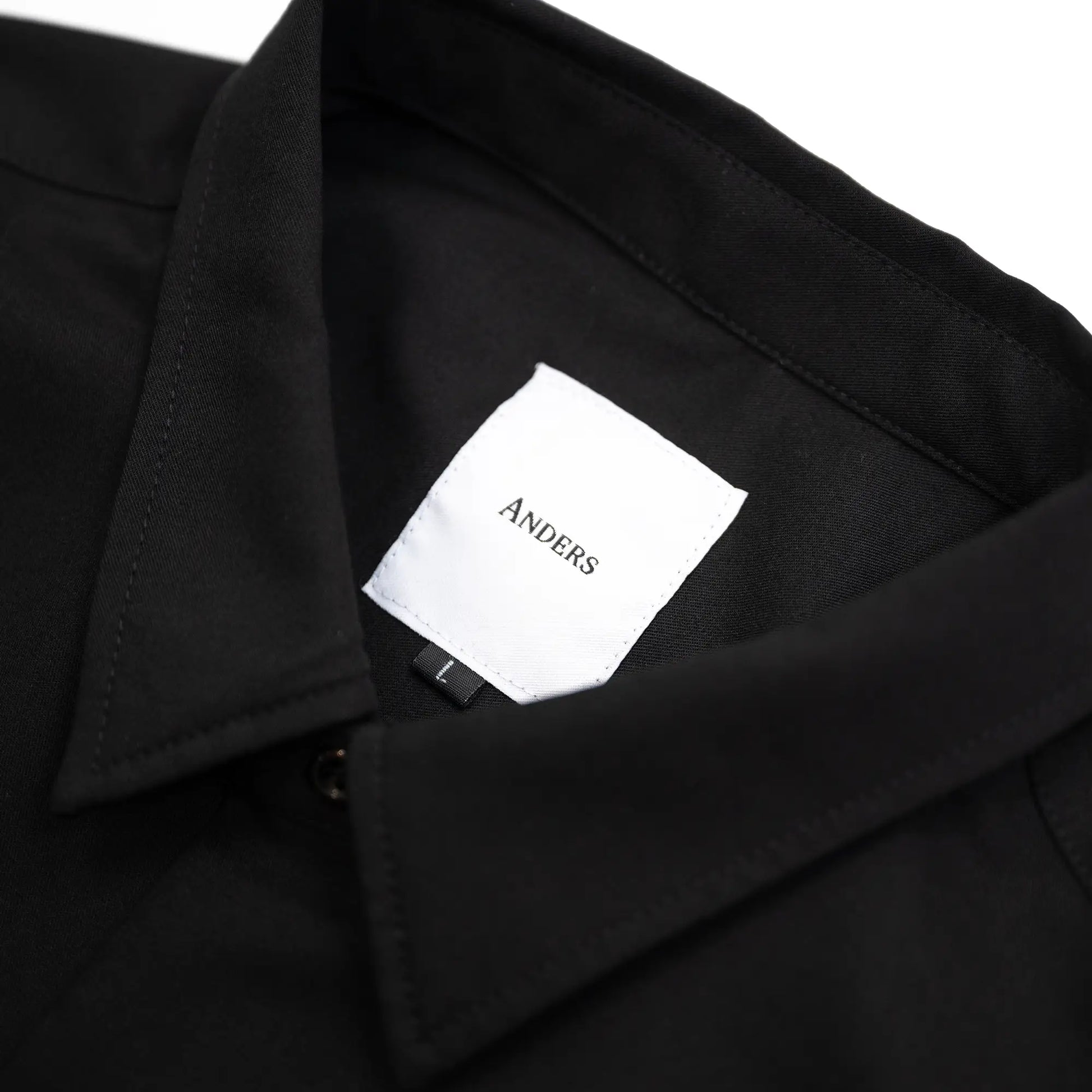 考え抜かれたワイドなボックスシルエットのAndersの傑作ドレープシャツ「WIDE DRAPE S/S SHIRTS」の「CROW」カラーの襟裏のブランドタグ写真
