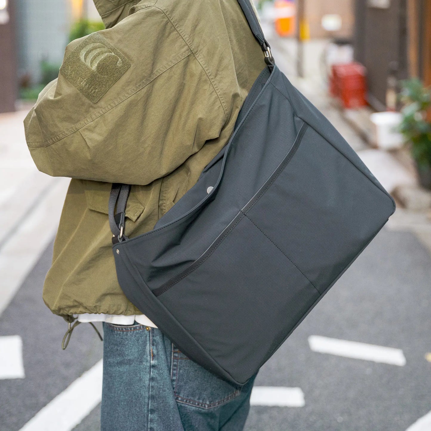 「TRIALOGUE STUDIO」のバッグ「ECLECTIC CROSSBODY BAG」を肩にかけた着用写真