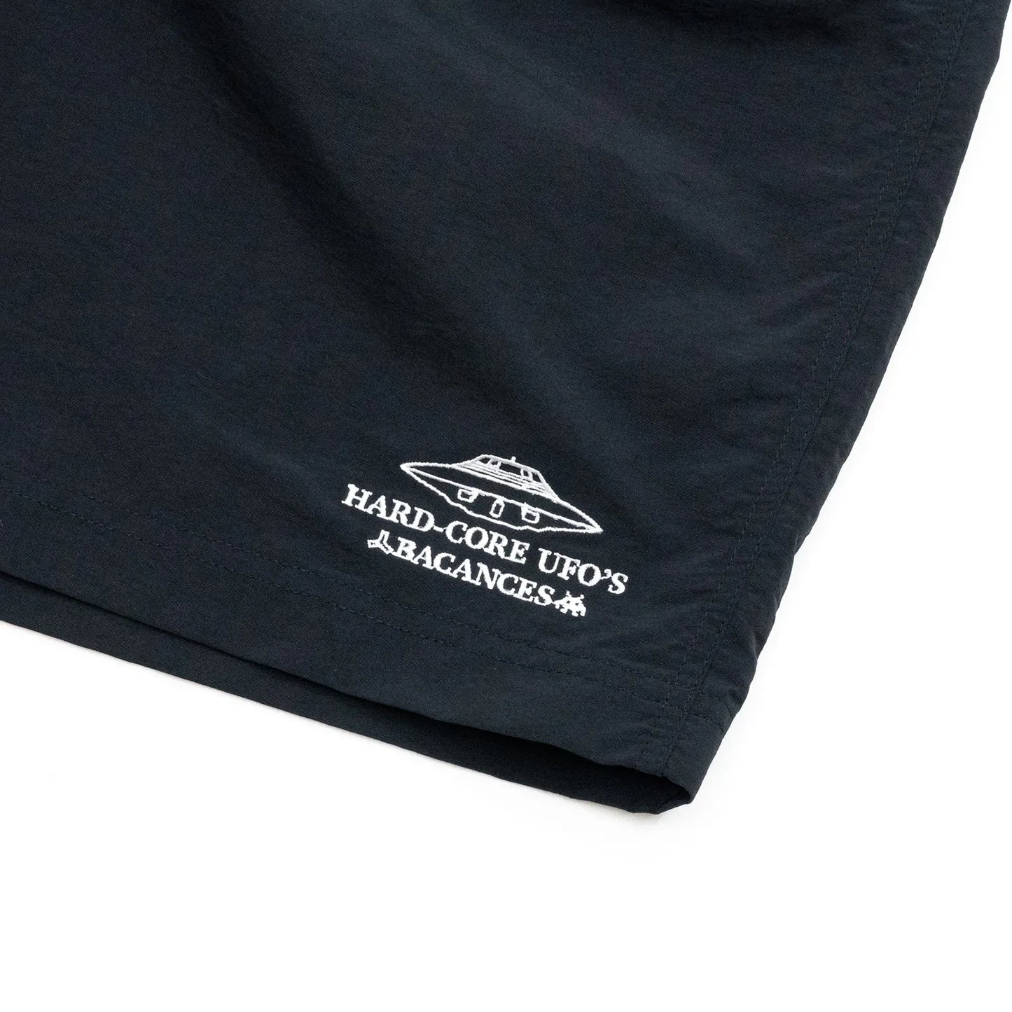 BACANCESのナイロン製の水陸両用ショーツ「BC NYLON SHORTS HARDCORE UFO'S LOGO」のBLACKカラーの左裾の刺繍デザインの写真