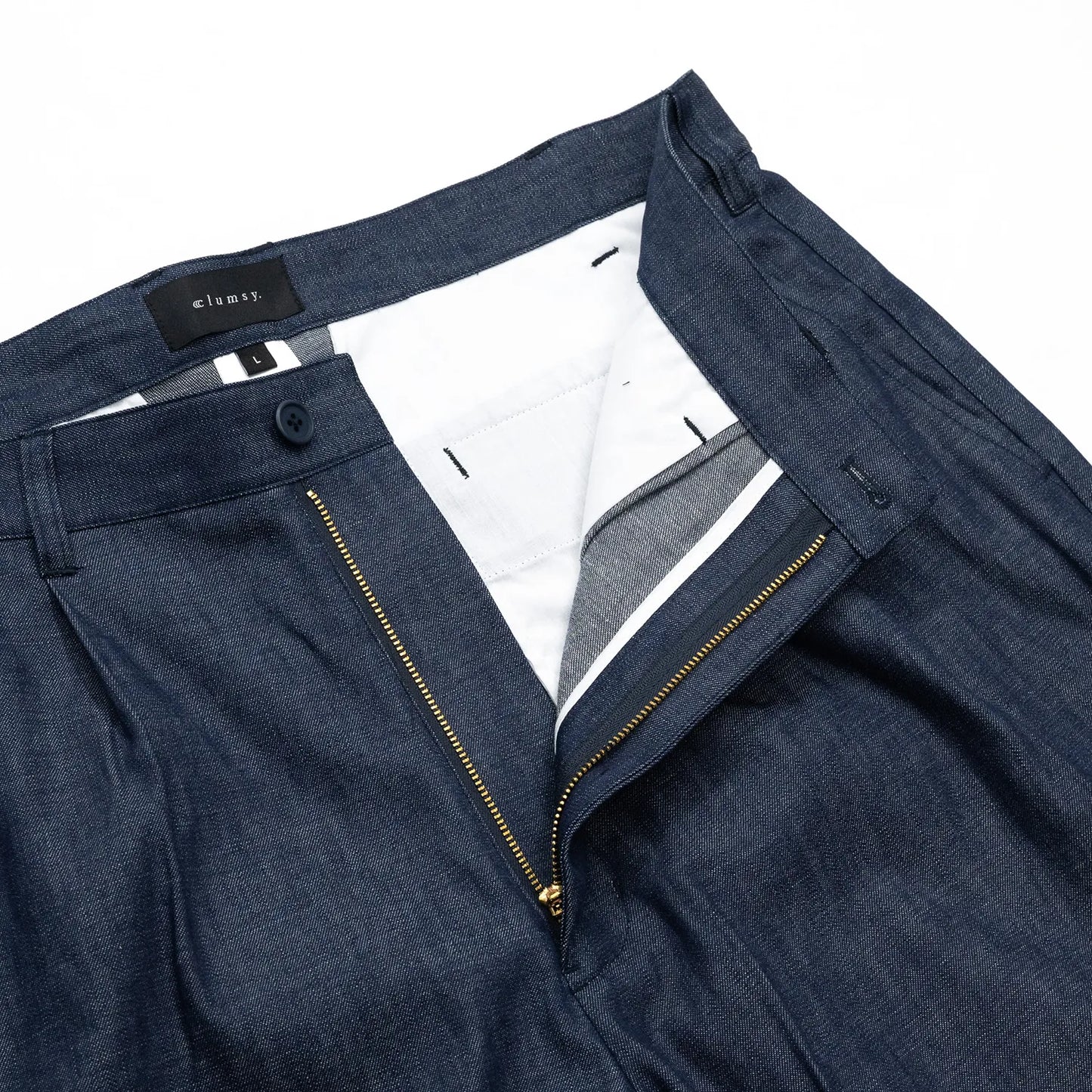clumsy. PICTURES(クラムジーピクチャーズ)のノンウォッシュの薄手デニム生地を使用した新作パンツ「2 PLEATS WIDE DENIM SLACKS」のINDIGOカラーのフロントジップ部分の写真