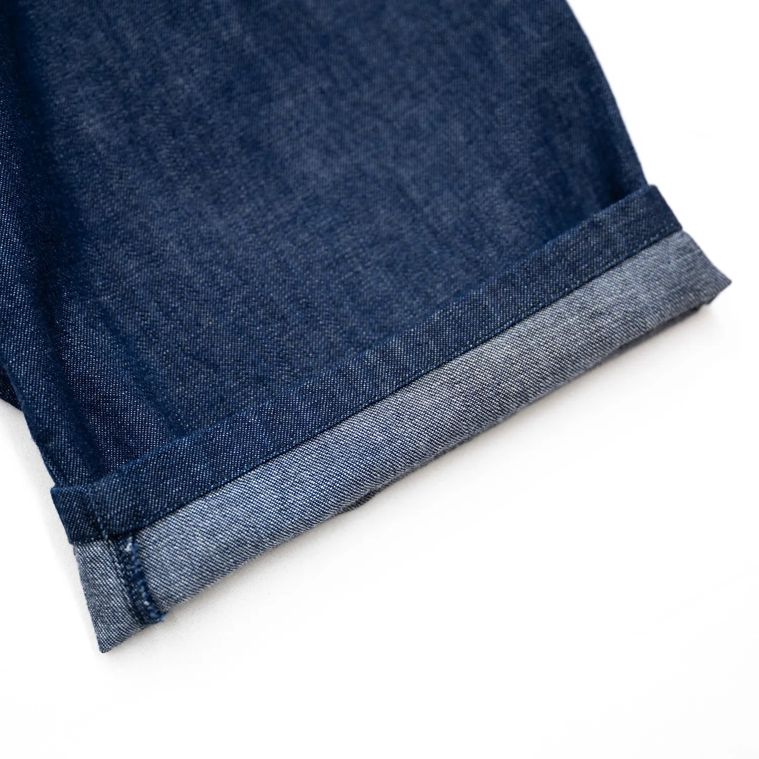 clumsy. PICTURES(クラムジーピクチャーズ)のウォッシュをかけた薄手のデニム生地を使用した新作パンツ「2 PLEATS WIDE DENIM SLACKS」のINDIGO WASHカラーの裾をターンアップした写真