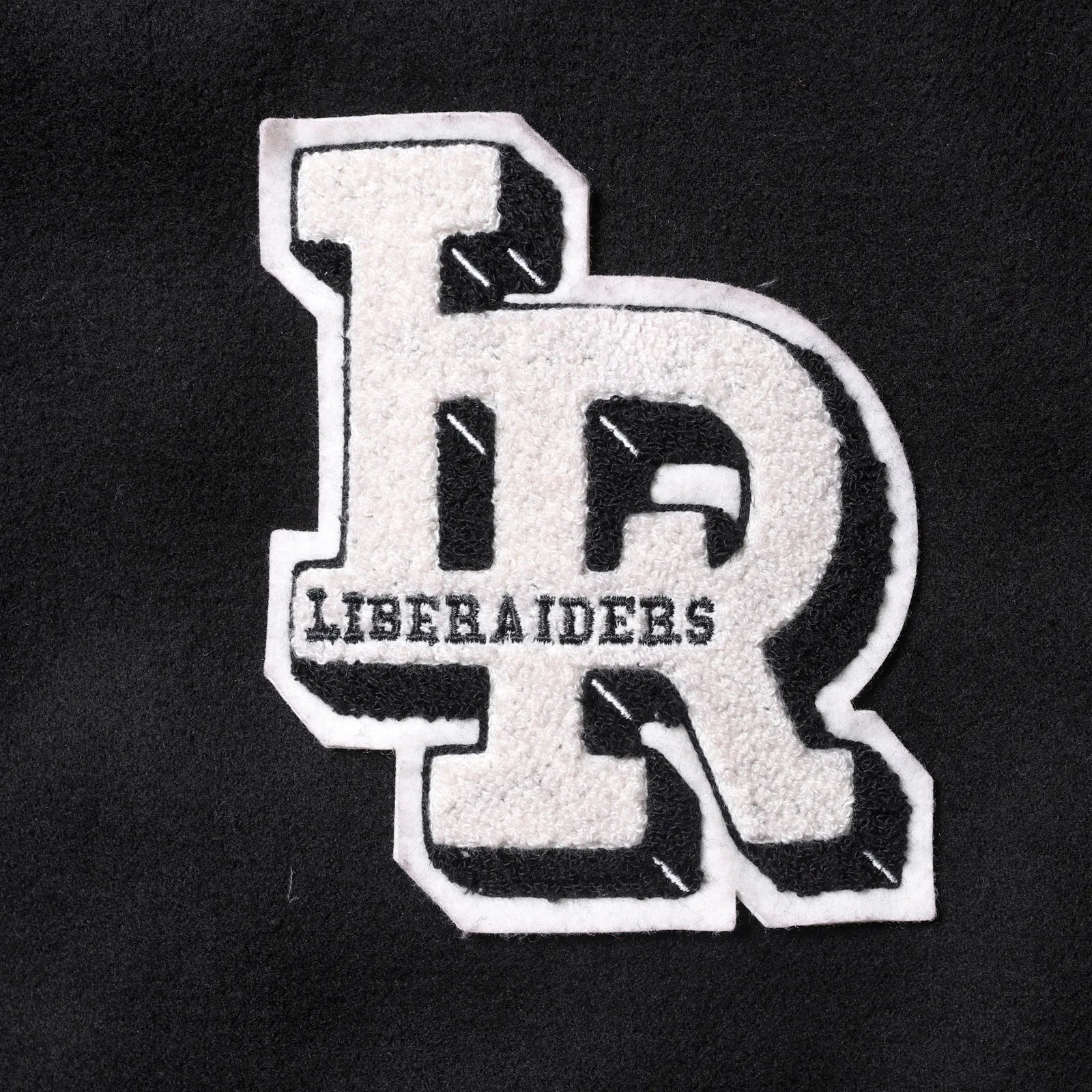 Liberaiders(リベレイダース)の肉厚なバーシティジャケット「LR VARSITY JACKET」のBLACKカラーの正面左胸のワッペンの写真