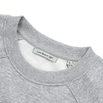 LAST RESORT AB(ラストリゾート)のアトラスロゴが左胸にプリントされたスエット「LITTLE AB RAGLAN CREW SWEAT」の「GREY MELANGED」カラーの襟元の写真