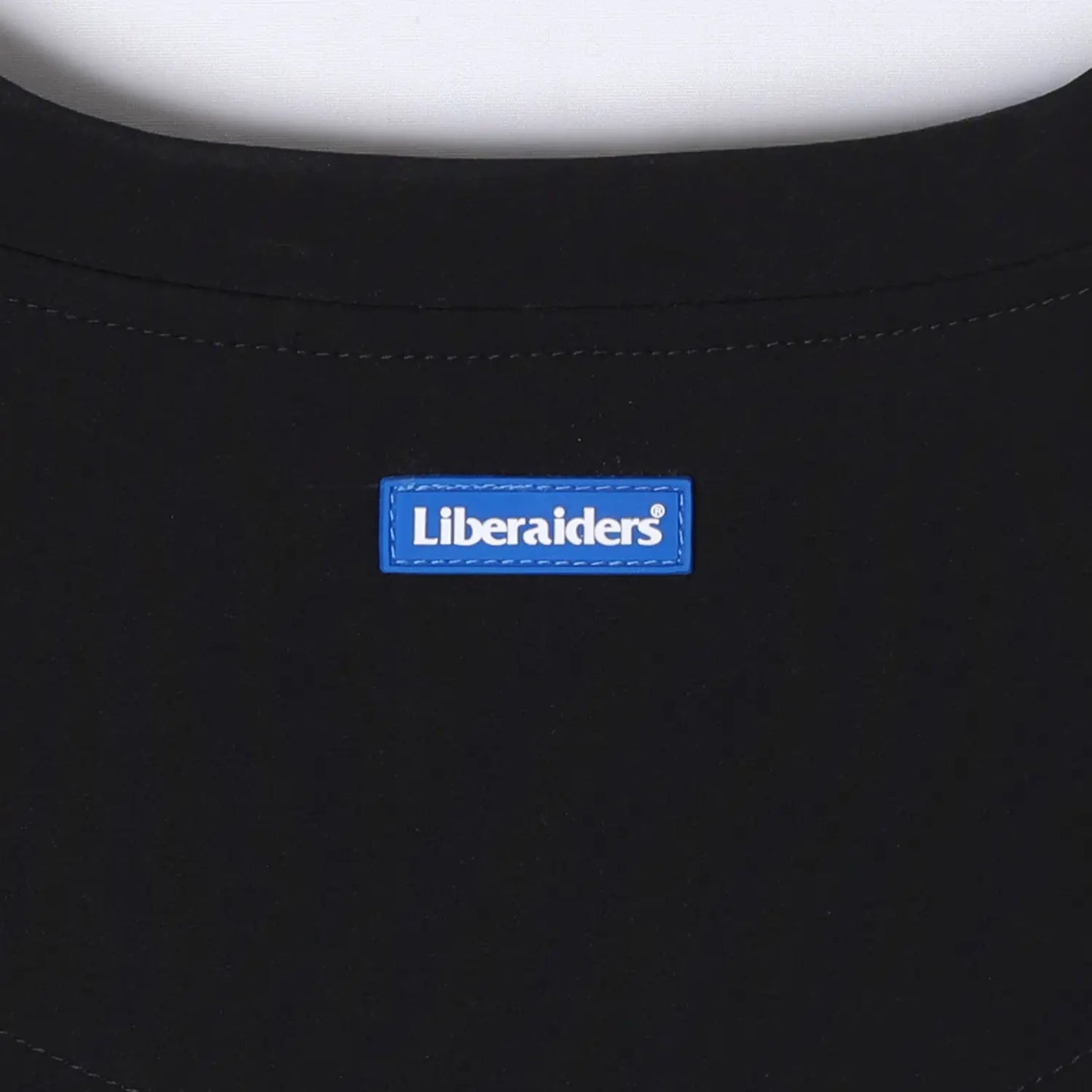 Liberaiders(リベレイダース)の撥水性のある4WAYストレッチ生地を使用したユーティリティTシャツ「4WAY STRETCH MULTI POCKET TEE」の BLACKカラーの後ろ襟元のブランドタグ写真