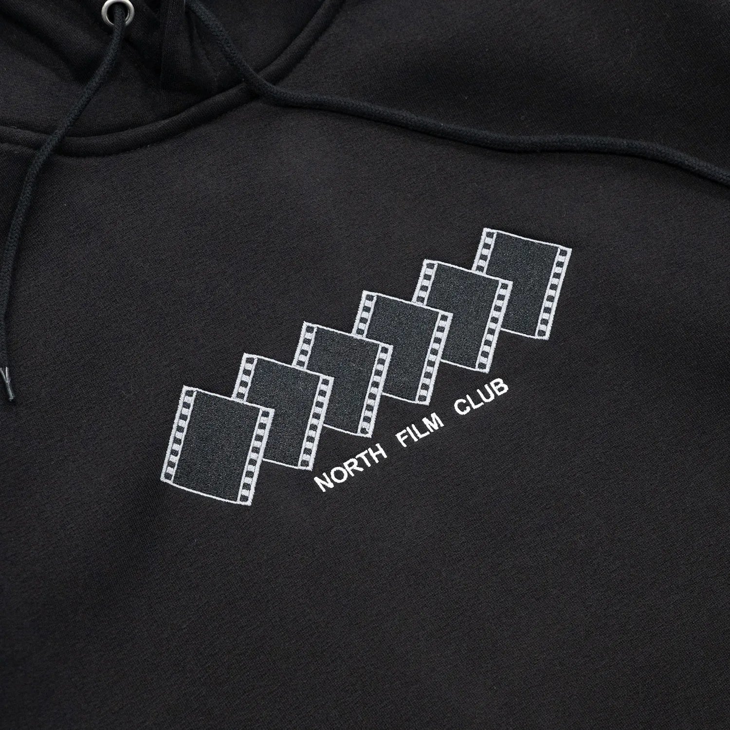 NORTH SKATE MAG(ノーススケートマグ)のフロントにデザインが刺繍で入る肉厚なパーカー「FILM CLUB HOODIE」のBLACKカラーの正面デザインの写真