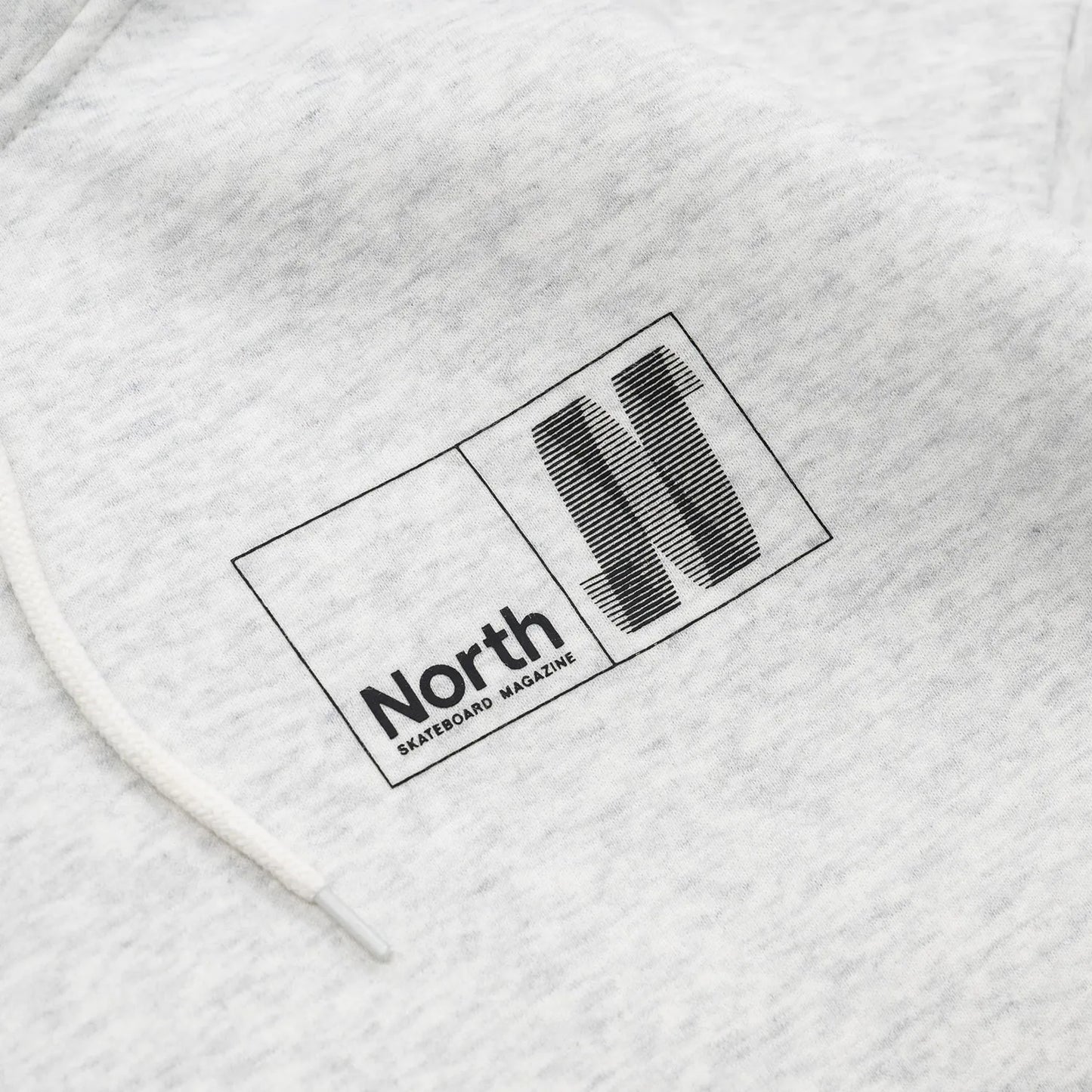 NORTH SKATE MAG(ノーススケートマグ)のバック大きく、フロント左胸にワンポイントでデザインがプリントされた肉厚なパーカー「N LOGO HOODIE」のASHカラーの襟元の写真