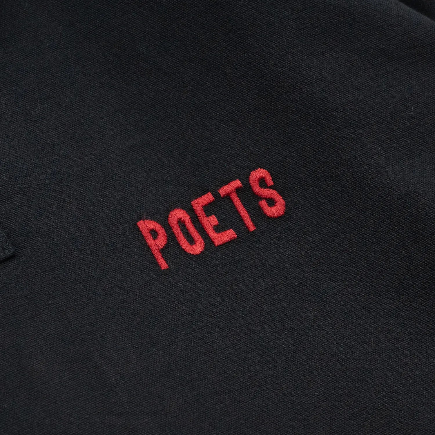 POETS(ポエッツ)の肉厚な生地を使用した2ボタンラガーシャツ「RUGBY WITH EMBROIDERED LOGO」のBLACKカラーの左胸のワンポイント刺繍デザインの写真