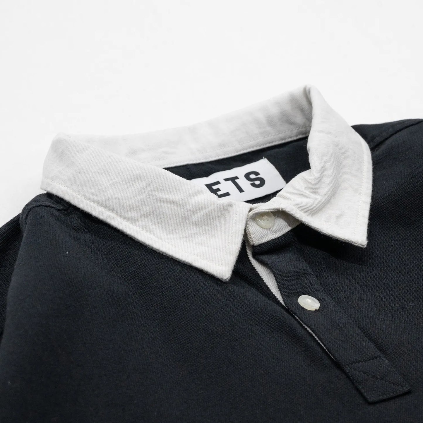 POETS(ポエッツ)の肉厚な生地を使用した2ボタンラガーシャツ「RUGBY WITH EMBROIDERED LOGO」のBLACKカラーの襟元の写真