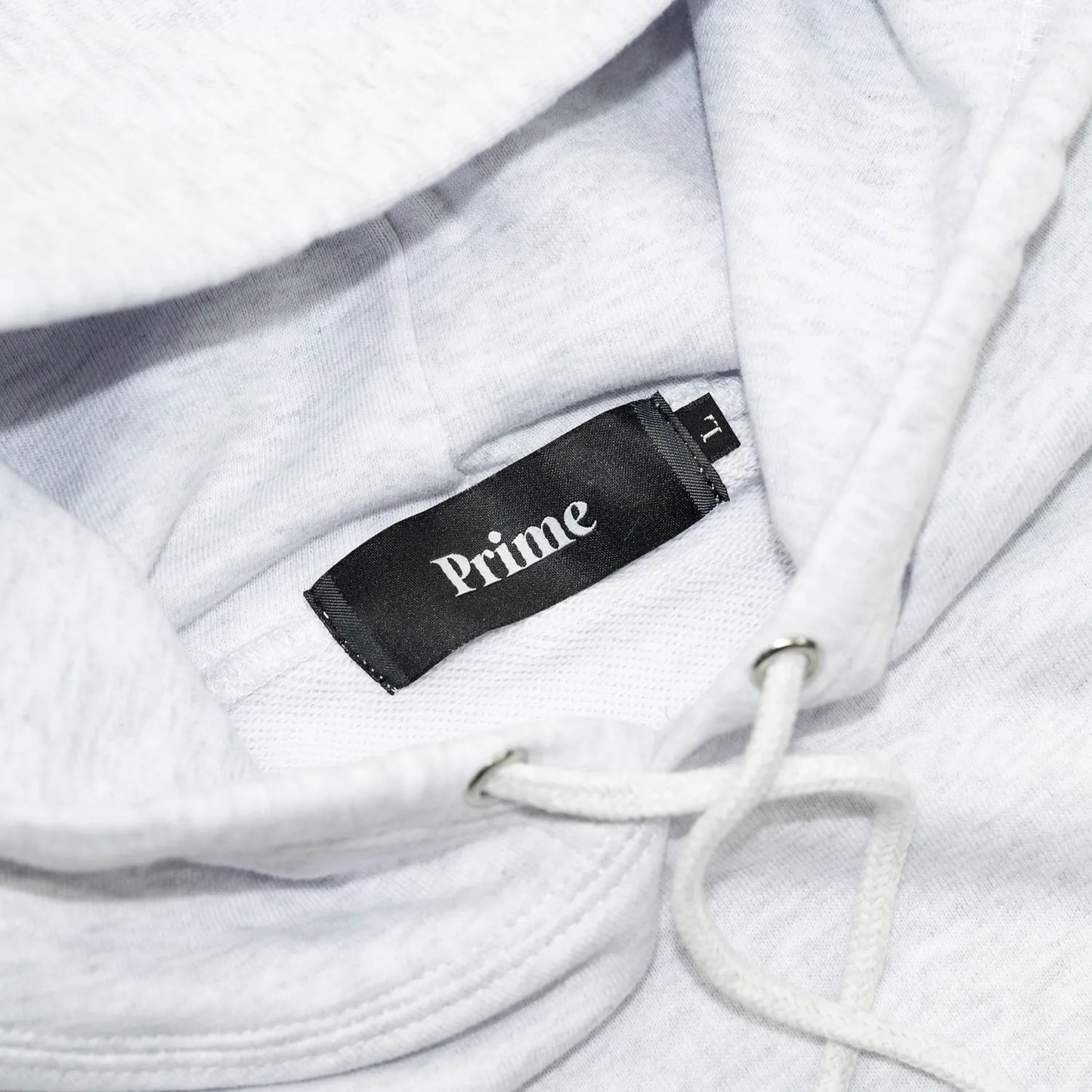 Primeのパーカー・フーディ「PRIME GALLERY BAR LOGO HOODY」のASHカラーの襟裏のブランドタグ