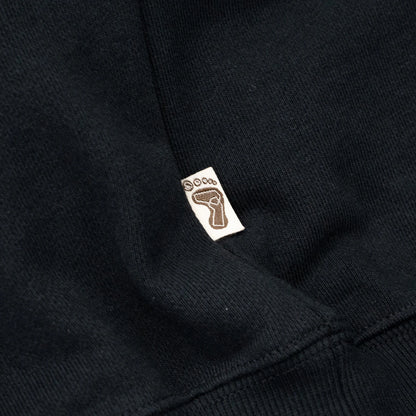 TRIBE WEAR(トライブウェア)の肉厚なフーディー｜パーカー「BASIC HOODIE」のBLACKカラーの左脇下のブランドタグ写真