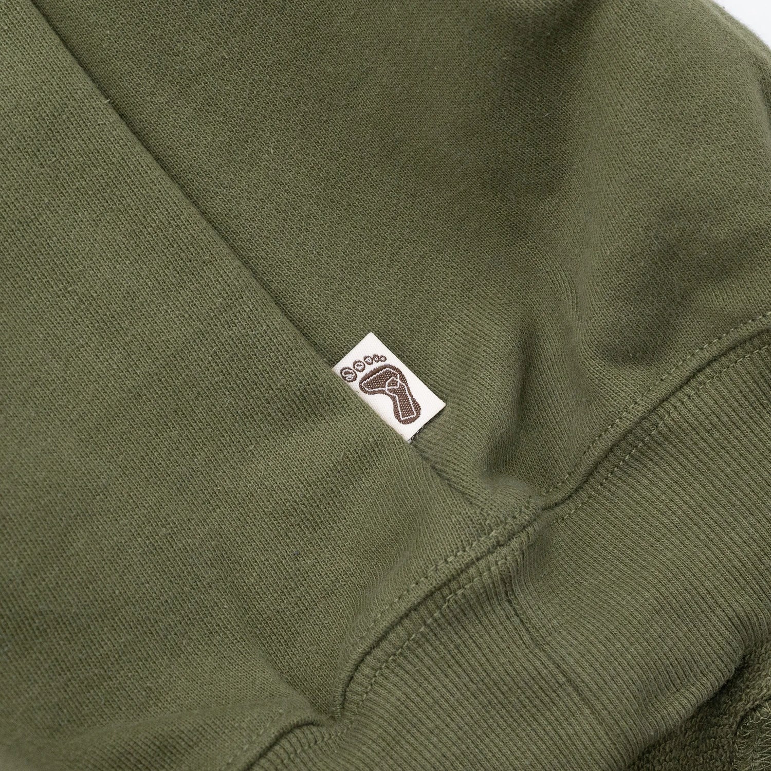 TRIBE WEAR(トライブウェア)の肉厚なフーディー｜パーカー「BASIC HOODIE」のOLIVEカラーの左脇下のブランドタグ写真