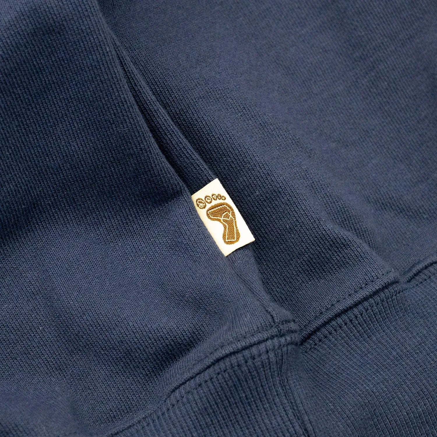 TRIBE WEAR(トライブウェア)の肉厚な生地感とファットなシルエットのクルーネックスエット「BASIC SWEAT CREWNECK」のNAVYカラーの左脇下のブランドタグの写真