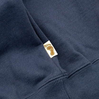 TRIBE WEAR(トライブウェア)の肉厚な生地感とファットなシルエットのクルーネックスエット「BASIC SWEAT CREWNECK」のNAVYカラーの左脇下のブランドタグの写真