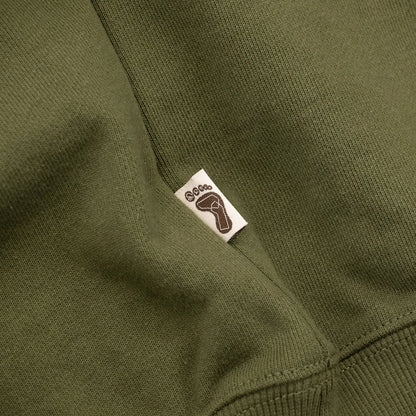 TRIBE WEAR(トライブウェア)の肉厚な生地感とファットなシルエットのクルーネックスエット「BASIC SWEAT CREWNECK」のOLIVEカラーの左脇下のブランドタグの写真