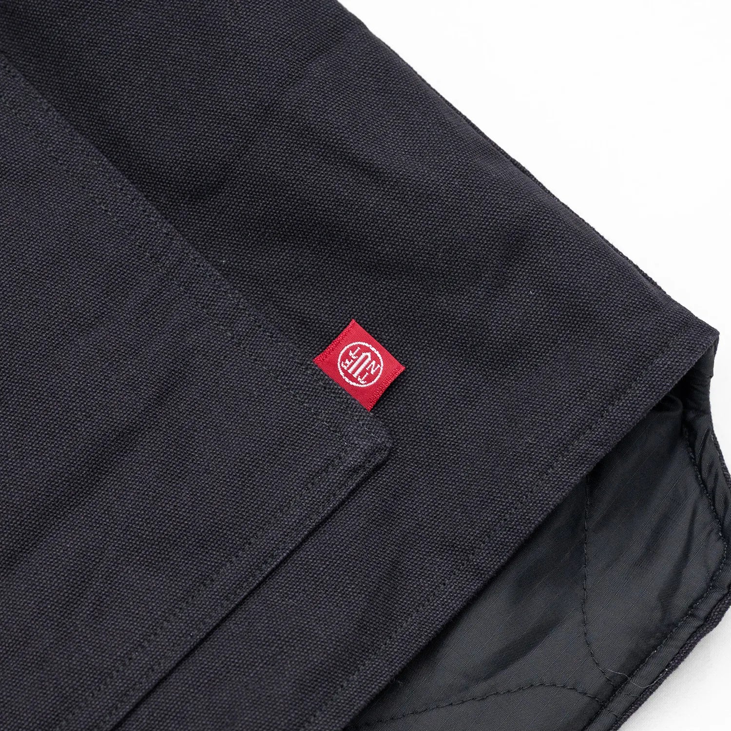 東洋エンタープライズによるTUF-NUT(タフナット)の12.5ozのコットンダック生地を使用した「COTTON DUCK WORK VEST」のBLACKカラーのフロント左ポケット脇のピスネームの写真