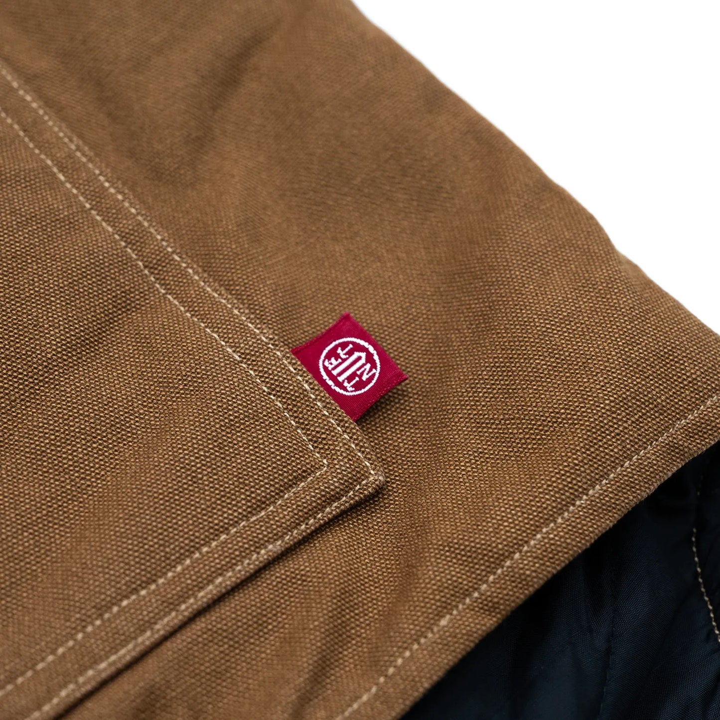 東洋エンタープライズによるTUF-NUT(タフナット)の12.5ozのコットンダック生地を使用した「COTTON DUCK WORK VEST」のCAMELカラーのフロント左ポケット脇のピスネームの写真